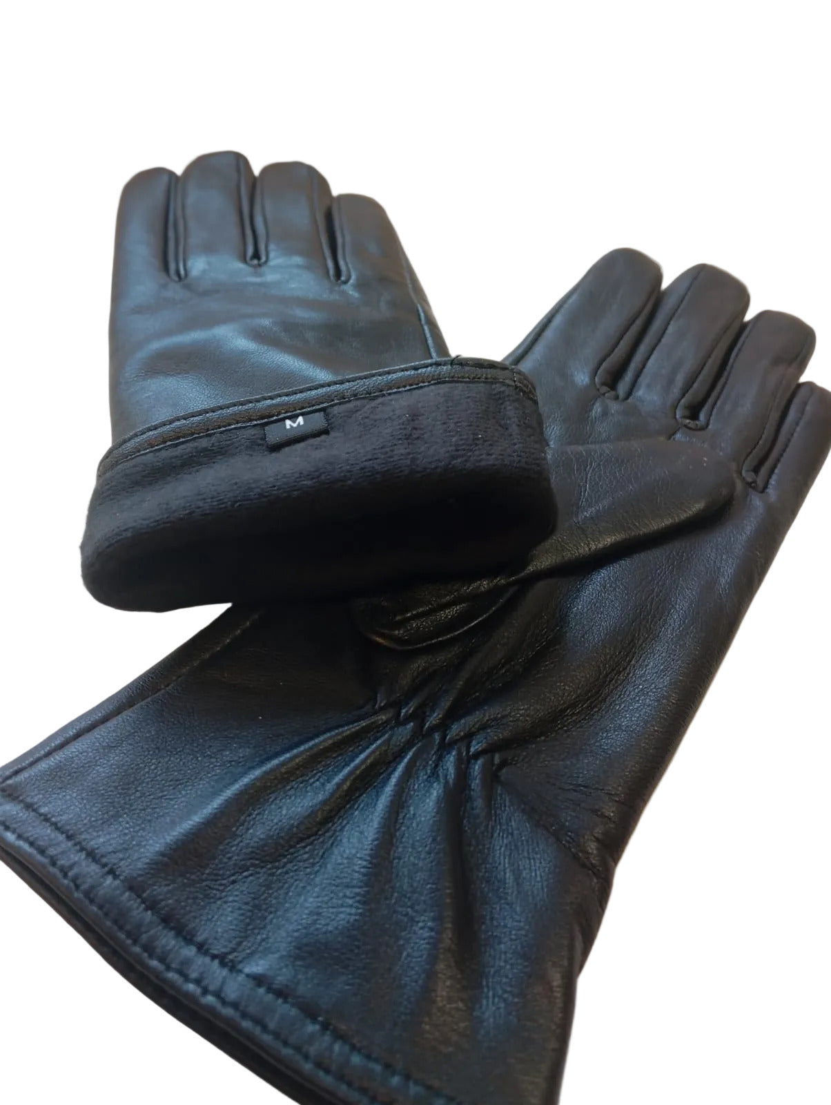 Pair of black leather gloves on a beige surface